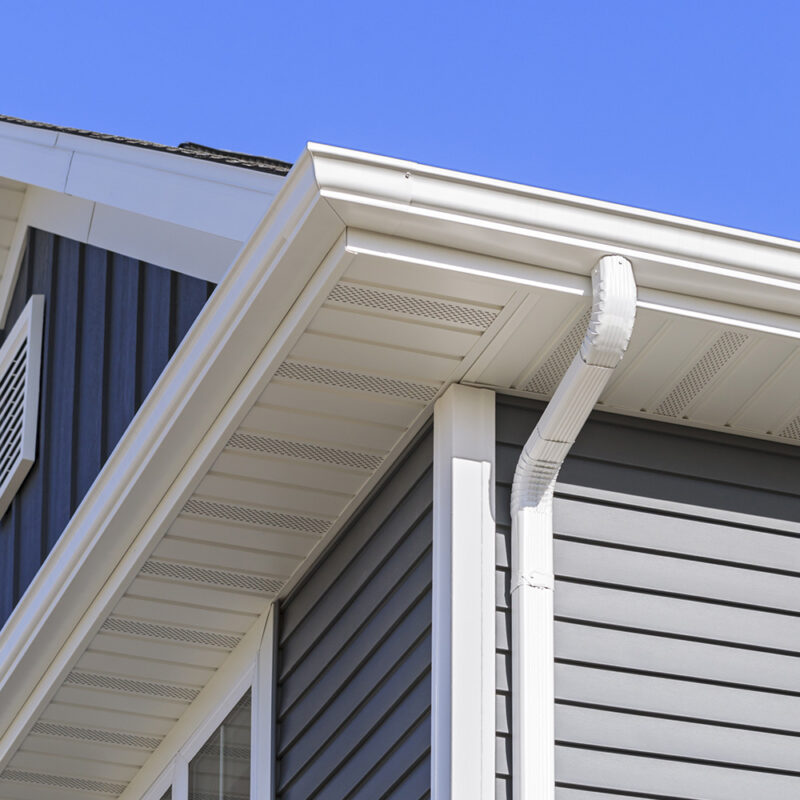 A close up of the corner of a house with white gutters
